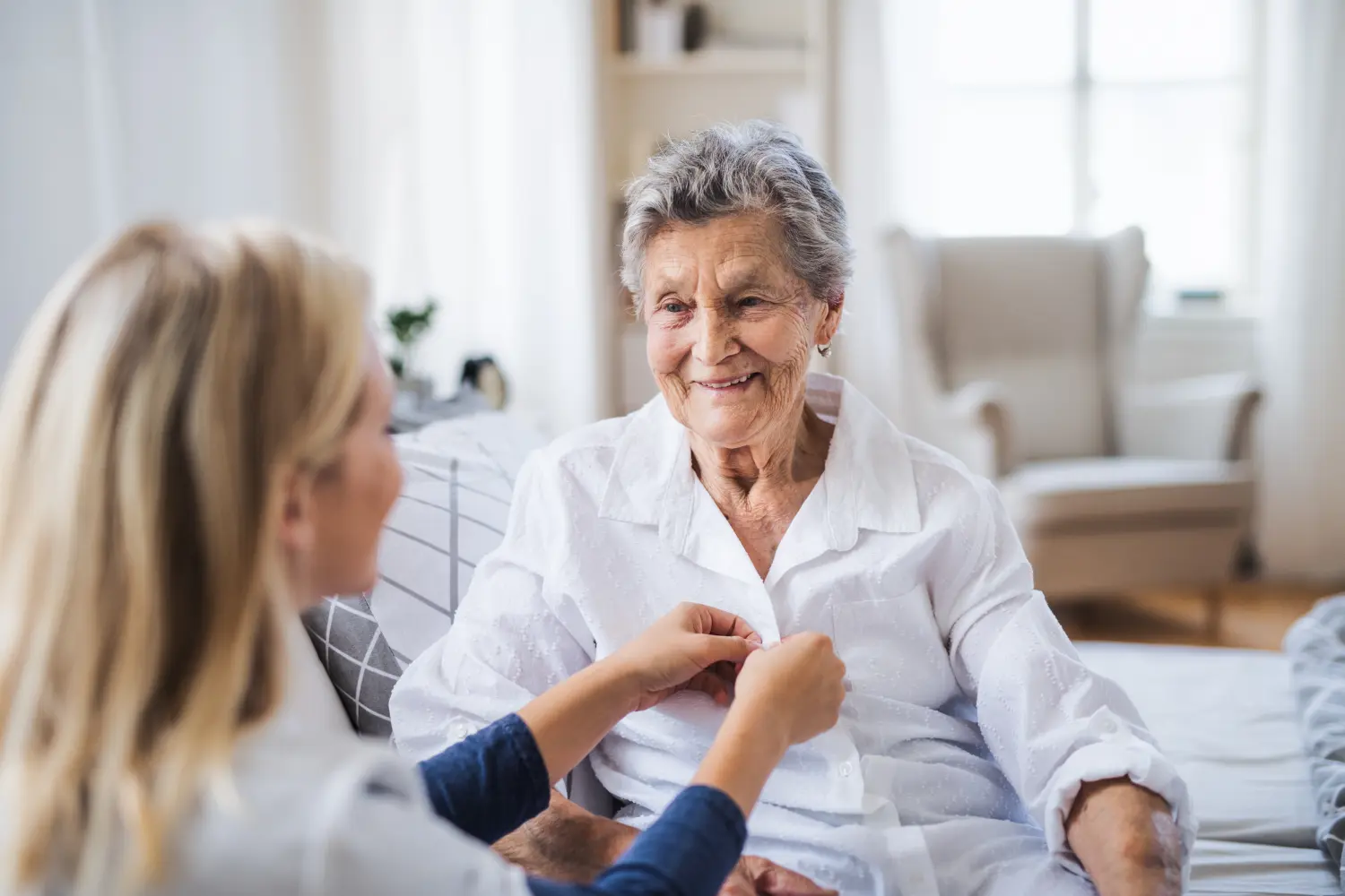 Eine Krankenschwester hilft einer kranken älteren Frau, die zu Hause im Bett sitzt.